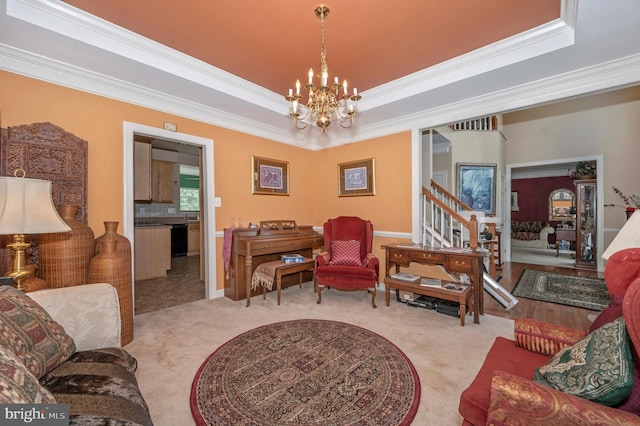 living room with crown molding, a raised ceiling, an inviting chandelier, and light colored carpet