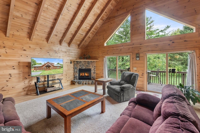 carpeted living room with wood walls, a stone fireplace, and high vaulted ceiling