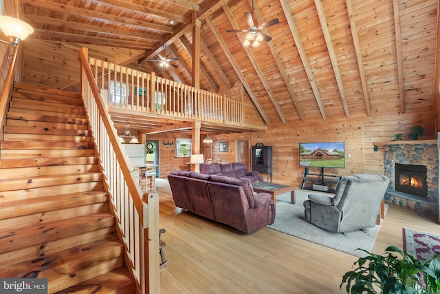 unfurnished living room featuring wooden ceiling, a fireplace, beam ceiling, ceiling fan, and light hardwood / wood-style flooring