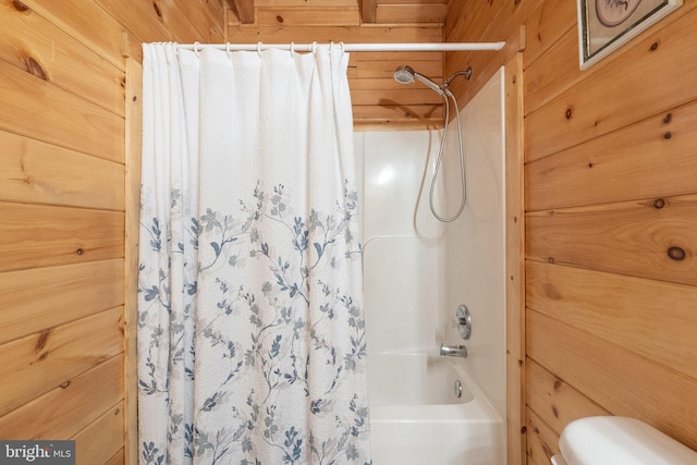 bathroom featuring shower / bathtub combination with curtain, wooden walls, and toilet