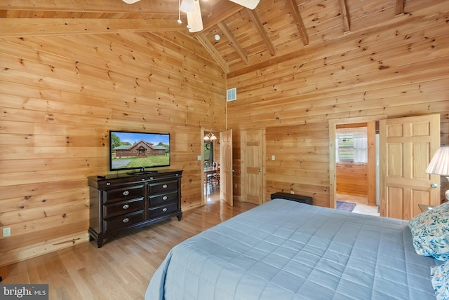 bedroom with wooden ceiling, beamed ceiling, wooden walls, and light hardwood / wood-style floors