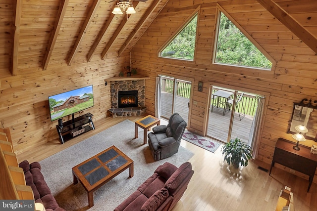 living room featuring wood walls, a stone fireplace, light hardwood / wood-style floors, and wood ceiling