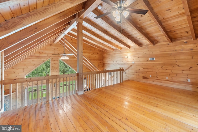 bonus room with light wood-type flooring, wooden ceiling, wooden walls, ceiling fan, and lofted ceiling with beams