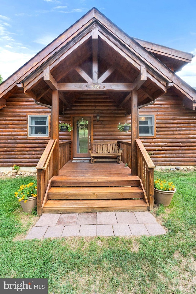 rear view of property with a wooden deck and a lawn