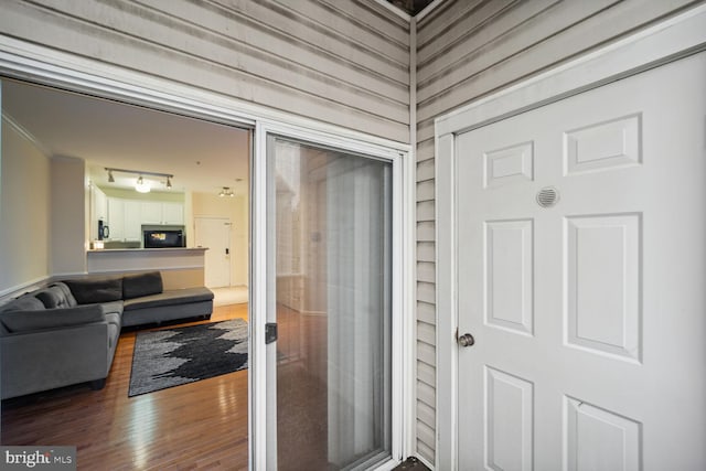 hallway with rail lighting, crown molding, and hardwood / wood-style floors