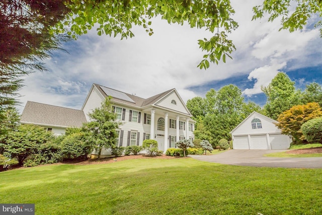 view of front of house featuring solar panels, an outdoor structure, a garage, and a front yard