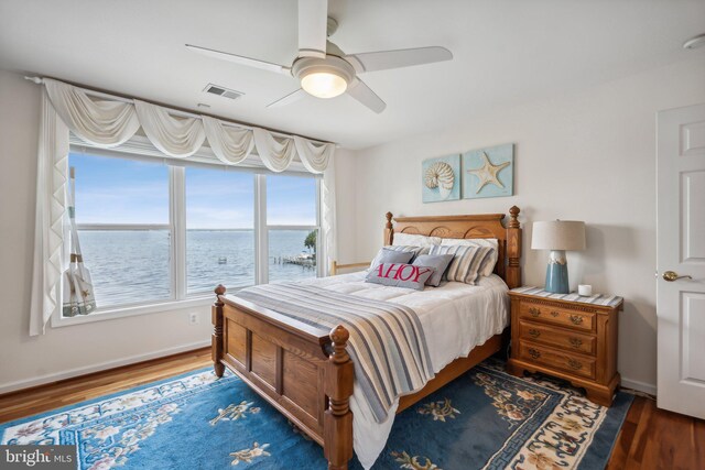 bedroom featuring ceiling fan, hardwood / wood-style flooring, and a water view