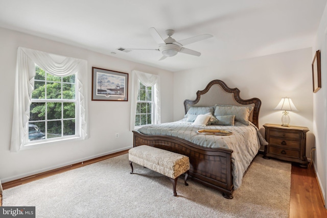 bedroom with multiple windows, ceiling fan, and wood-type flooring