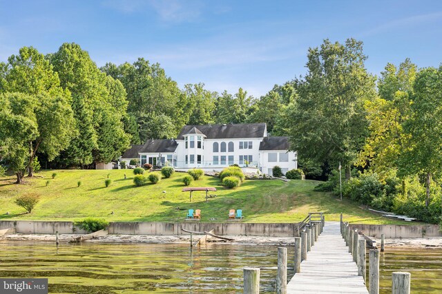 rear view of property featuring a lawn and a water view