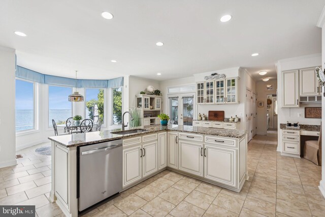 kitchen featuring pendant lighting, dishwasher, light stone countertops, sink, and light tile patterned flooring