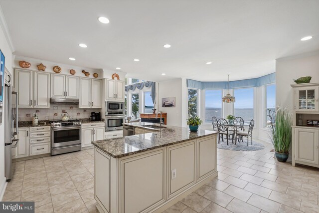 kitchen with tasteful backsplash, sink, dark stone countertops, decorative light fixtures, and stainless steel appliances