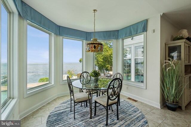 dining space featuring a water view and light tile patterned floors