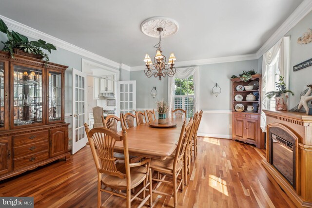 dining space with crown molding, light hardwood / wood-style flooring, and a chandelier