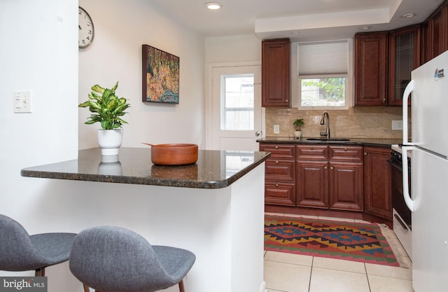 kitchen with white fridge, a breakfast bar, sink, and light tile patterned floors