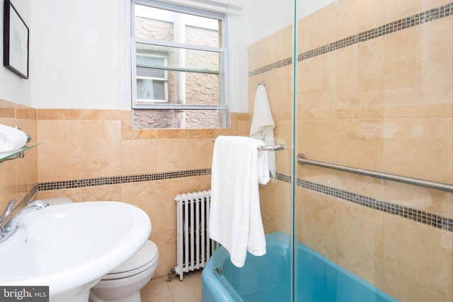 bathroom with sink, shower / bath combination with glass door, tile walls, radiator, and tile patterned flooring