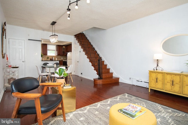 living room with a baseboard heating unit, dark wood-type flooring, and a textured ceiling