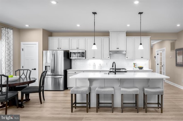 kitchen featuring an island with sink, stainless steel appliances, light hardwood / wood-style floors, and white cabinetry