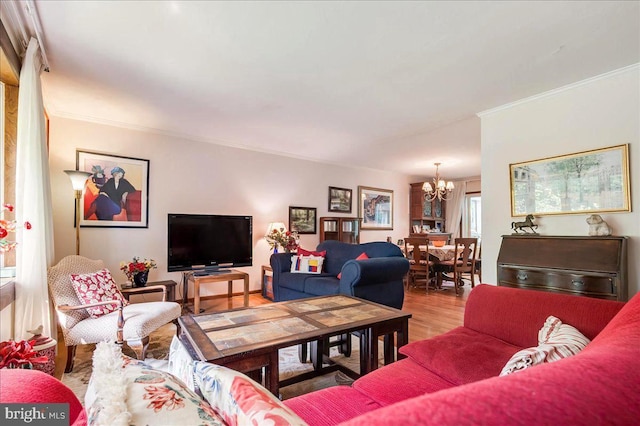 living area with light wood-style floors, ornamental molding, and an inviting chandelier