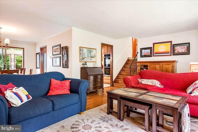 living room featuring a notable chandelier, stairs, crown molding, and wood finished floors