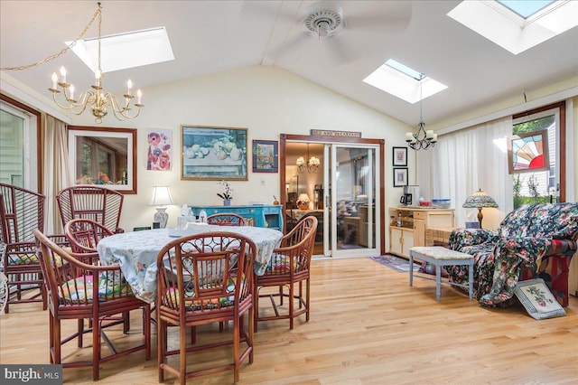 dining area featuring light wood-type flooring, lofted ceiling with skylight, and a notable chandelier