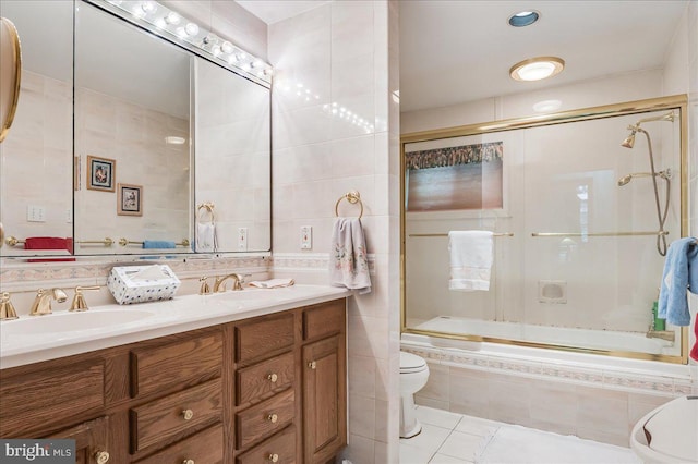 bathroom with toilet, tiled shower / bath combo, tile walls, and a sink