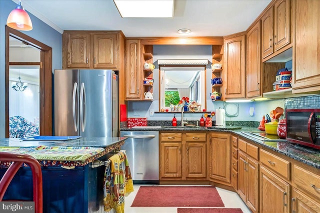 kitchen with appliances with stainless steel finishes, sink, dark stone countertops, and pendant lighting