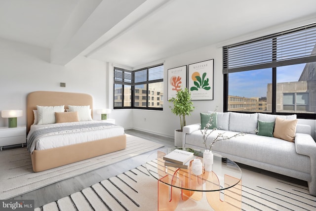 bedroom with beamed ceiling, wood finished floors, and baseboards