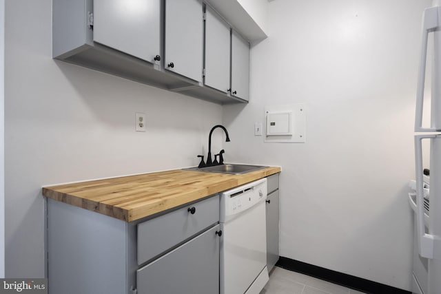 kitchen with white appliances, light tile patterned floors, baseboards, gray cabinets, and a sink