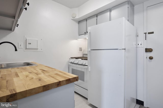 kitchen with under cabinet range hood, butcher block countertops, white appliances, and a sink