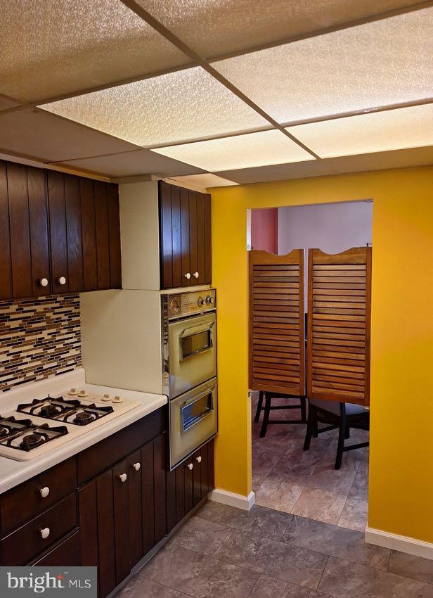 kitchen featuring dark brown cabinetry, white gas cooktop, and tasteful backsplash