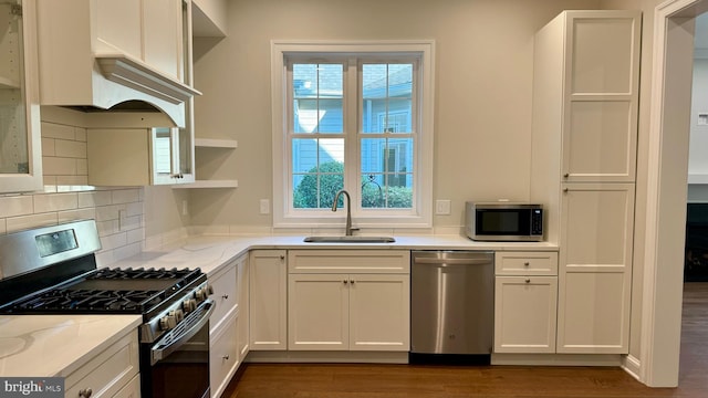 kitchen with stainless steel appliances, dark wood-type flooring, light stone counters, white cabinets, and sink