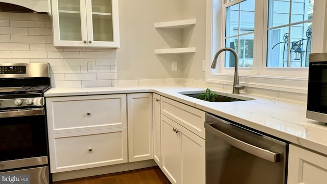 kitchen with white cabinetry, light stone countertops, sink, and stainless steel appliances