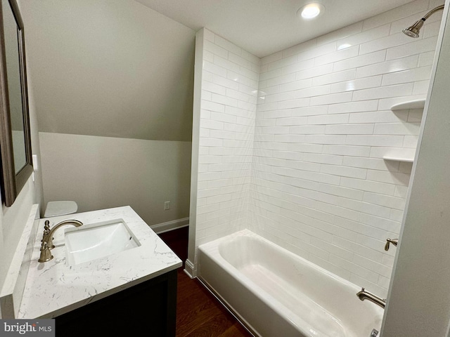 full bathroom featuring wood-type flooring, vanity, toilet, and tiled shower / bath combo