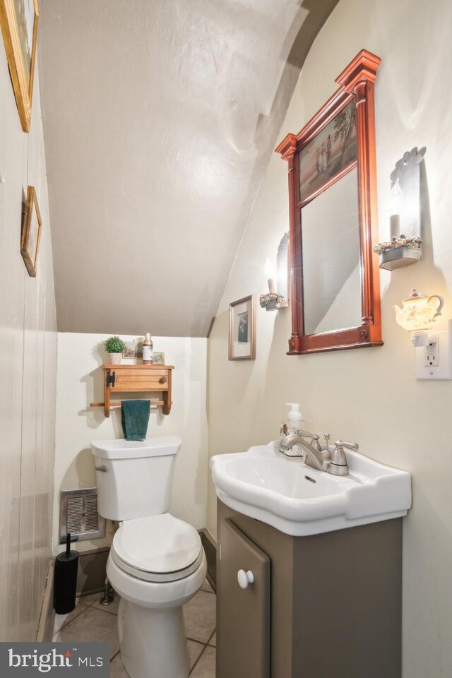 bathroom featuring toilet, vanity, vaulted ceiling, and tile patterned flooring