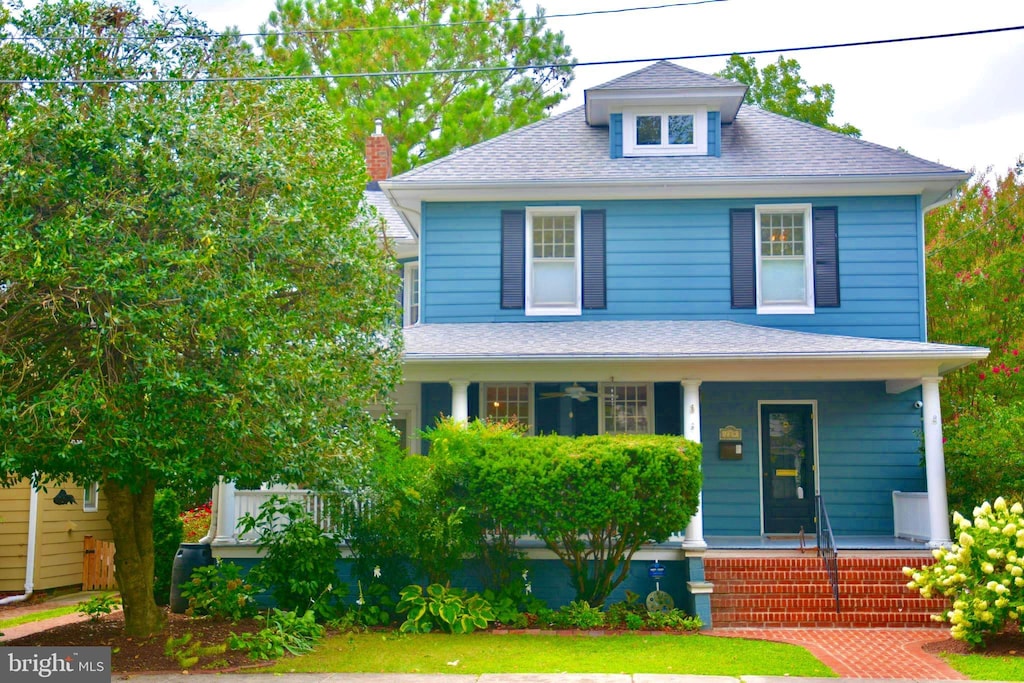 american foursquare style home featuring covered porch and roof with shingles