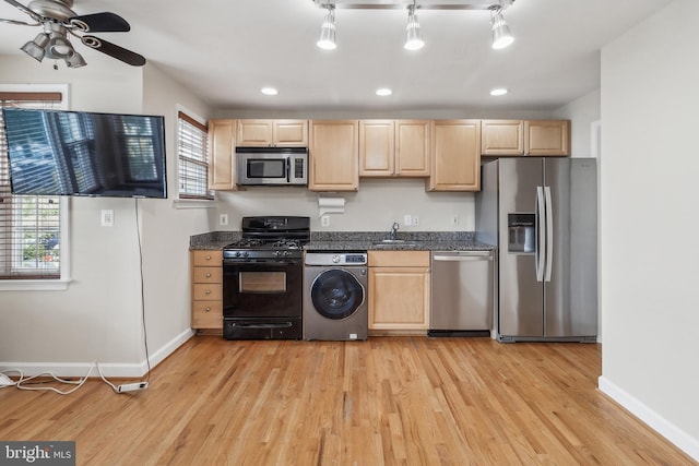 kitchen with stainless steel appliances, light brown cabinets, washer / dryer, light wood-type flooring, and baseboards