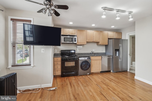 kitchen with stainless steel appliances, dark countertops, radiator heating unit, light brown cabinetry, and washer / dryer