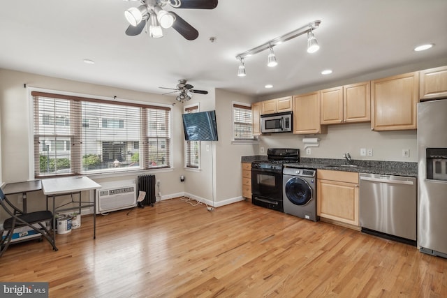 kitchen featuring light wood finished floors, stainless steel appliances, washer / clothes dryer, and a sink