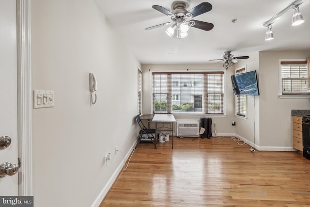 interior space with baseboards, light wood-style floors, a wall mounted air conditioner, and a healthy amount of sunlight