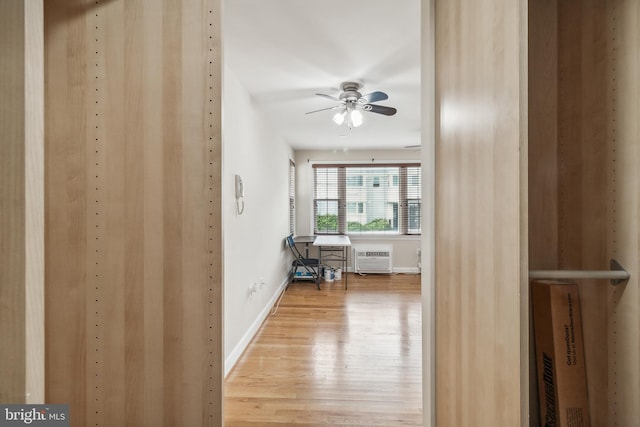 hallway featuring an AC wall unit, light wood-style flooring, and baseboards