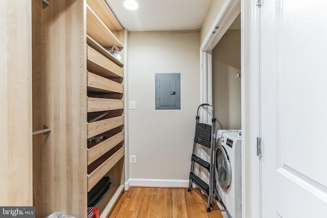 washroom with light wood-style flooring, laundry area, baseboards, electric panel, and washer / dryer