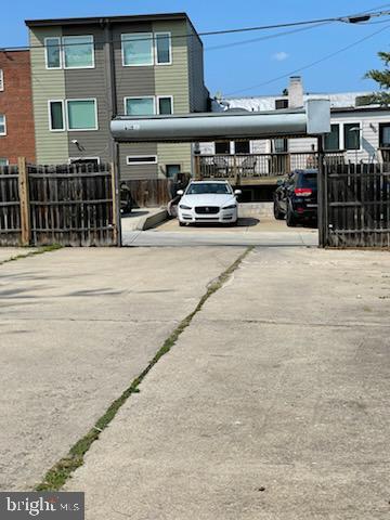 view of vehicle parking with concrete driveway and fence