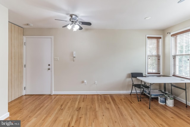 home office featuring light wood-type flooring, ceiling fan, and baseboards