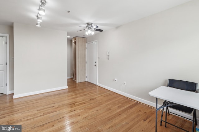 interior space featuring light wood finished floors, baseboards, and a ceiling fan