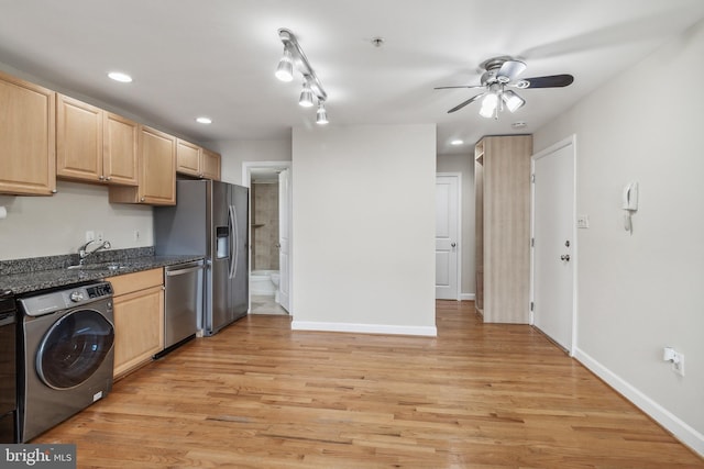 kitchen featuring washer / clothes dryer, appliances with stainless steel finishes, light brown cabinets, a sink, and dark stone countertops