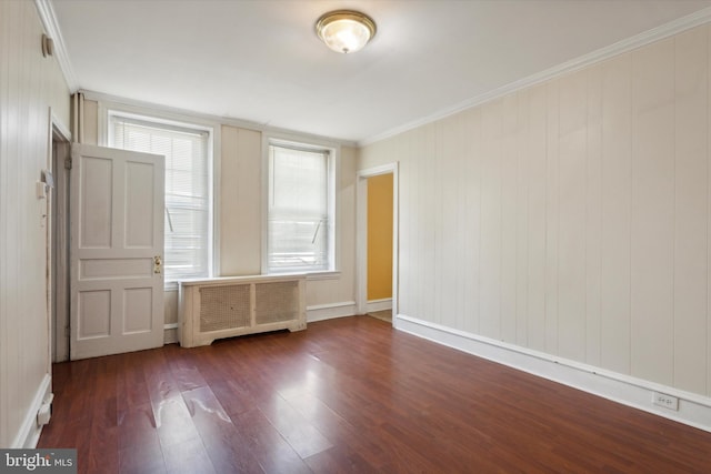 empty room featuring dark hardwood / wood-style flooring, crown molding, and radiator heating unit