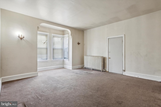 spare room featuring carpet and radiator heating unit