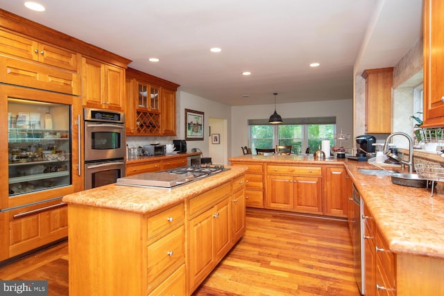 kitchen with light hardwood / wood-style flooring, pendant lighting, backsplash, stainless steel appliances, and a kitchen island