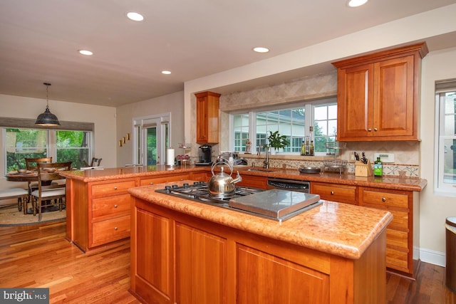 kitchen featuring a center island, light stone countertops, backsplash, light hardwood / wood-style floors, and kitchen peninsula