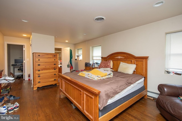 bedroom with a baseboard heating unit and dark hardwood / wood-style floors